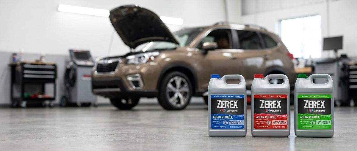 Valvoline Zerex Asian ანტიფრიზის სამი კანისტრა ავტოსახელოსნოში, გახსნილი კაპოტის მქონე ავტომობილის წინ